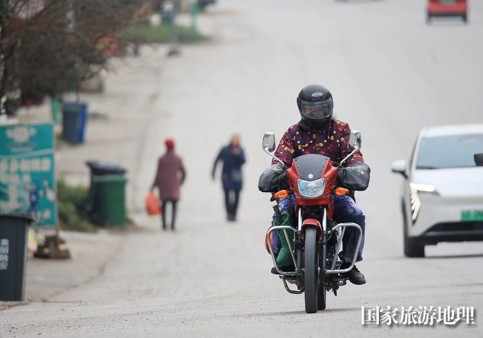 图2：1月26日，在国道209线广西柳州市融安县浮石镇路段，务工人员骑摩托车回家过年。（谭凯兴摄）