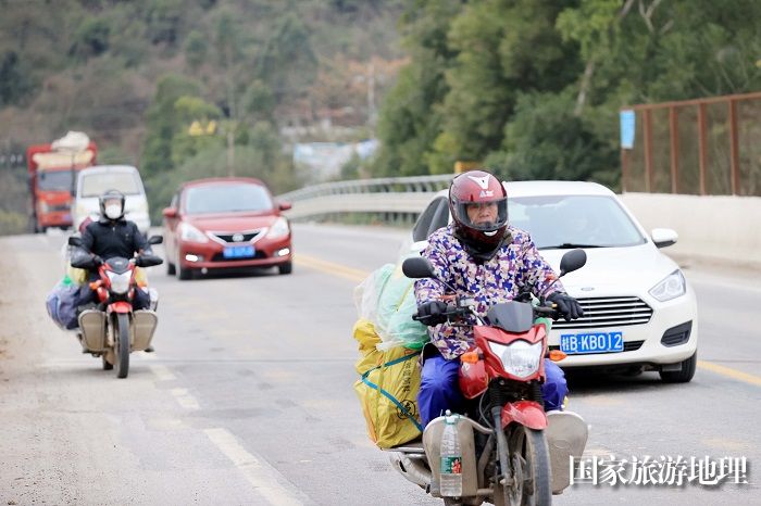 图4：1月26日，在国道209线广西柳州市融安县长安镇大坡村路段，务工人员骑摩托车回家过年。（谭凯兴摄）
