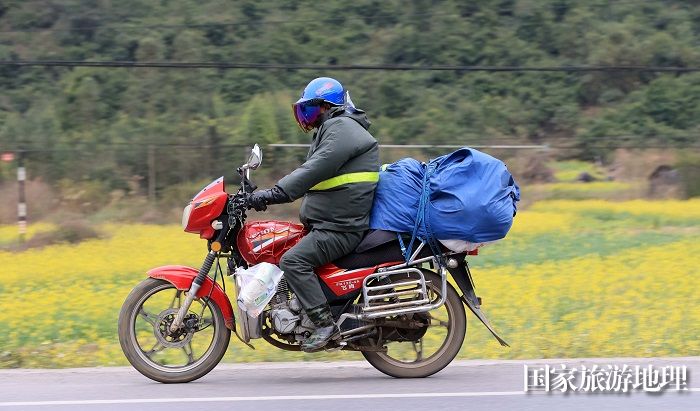图7：1月26日，在国道209线广西柳州市融安县浮石镇桥头村路段，务工人员骑摩托车回家过年。（谭凯兴摄）