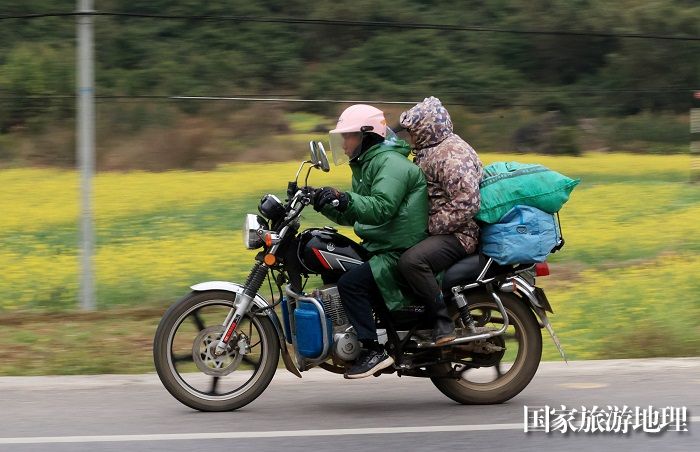 图8：1月26日，在国道209线广西柳州市融安县浮石镇桥头村路段，务工人员骑摩托车回家过年。（谭凯兴摄）