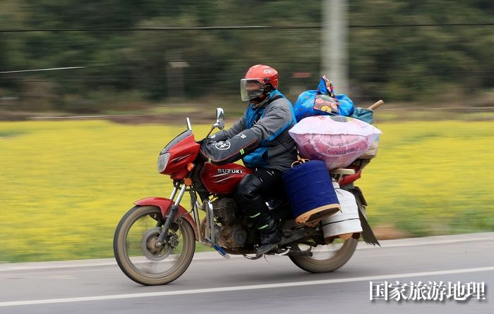 图10：1月26日，在国道209线广西柳州市融安县浮石镇桥头村路段，务工人员骑摩托车回家过年。（谭凯兴摄）