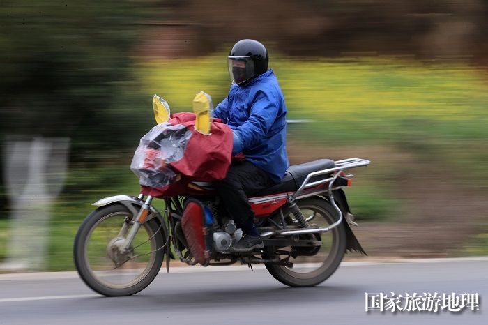 图11：1月26日，在国道209线广西柳州市融安县浮石镇桥头村路段，务工人员骑摩托车回家过年。（谭凯兴摄）