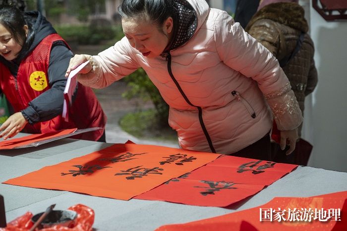 14、2024年1月27日，在广西梧州市万秀区蓝天港湾小区迎春文化活动现场，志愿者为居民写春联。（何华文）