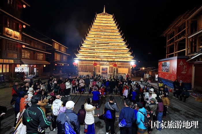 图2：2月1日晚，在广西柳州市三江侗族自治县林溪乡程阳八寨，侗族群众和游客在跳竹竿舞。（谭凯兴 摄）