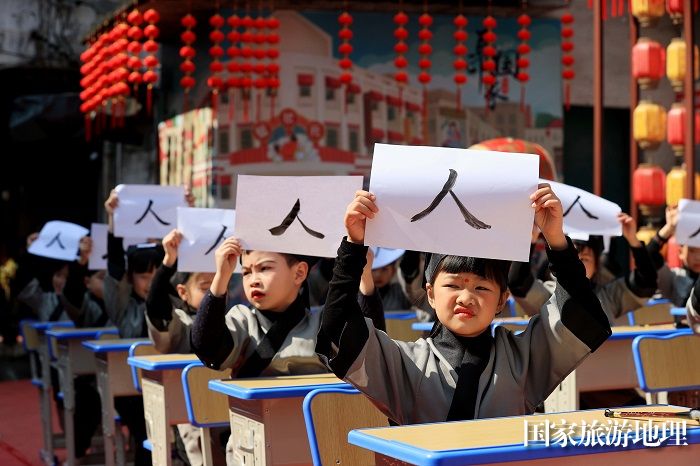 图1：3月11日，在广西柳州市融安县长安镇骑楼街举行的“开笔礼”仪式上，学生们在展示书写的人字。（谭凯兴 摄）