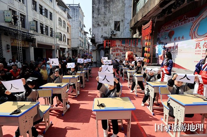 图2：3月11日，在广西柳州市融安县长安镇骑楼街举行的“开笔礼”仪式上，学生们在展示书写的人字。（谭凯兴 摄）