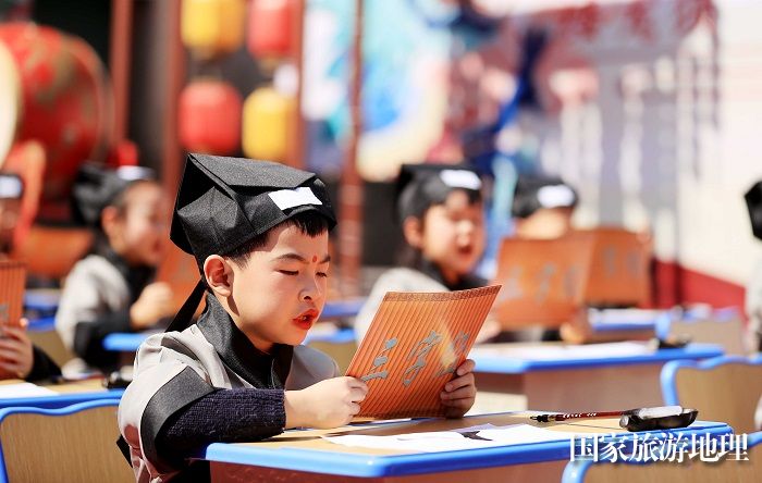 图5：3月11日，在广西柳州市融安县长安镇骑楼街，一年级新生在“开笔礼”仪式上朗读《弟子规》。（谭凯兴 摄）