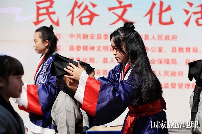 图6：3月11日，在广西柳州市融安县长安镇骑楼街，老师们在“开笔礼”仪式上为学生“正衣冠”。（谭凯兴 摄）