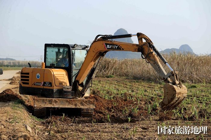 图3：3月19日，在广西柳州市融安县潭头乡新林村，农民驾驶挖掘机整地。（谭凯兴 摄）