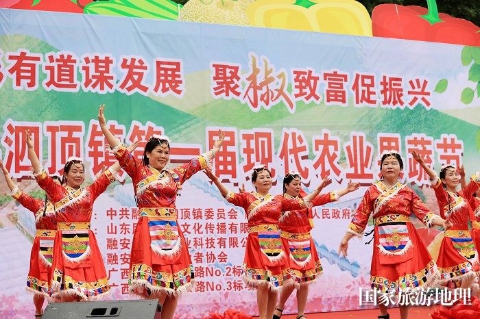 图5：5月1日，在广西柳州市融安县泗顶镇儒南村拉井屯，工作人员在第一届果蔬节上表演民族舞蹈。（谭凯兴 摄）