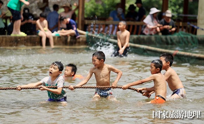 图10：7月11日，在广西柳州市融安县长安镇安宁村大袍苗寨，小朋友在水池中玩拔河游戏。（谭凯兴 摄）