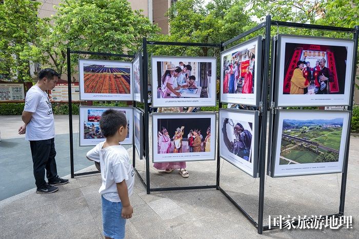 1、2024年7月20日，居民在广西梧州市万秀区蓝天社区蓝天港湾小区观看摄影展。（何华文）